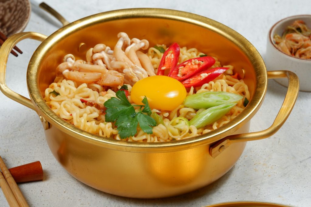 Serving a Korean style instant noodle, Ramyeon or Ramyun with spicy flavour topped with egg yolk, ch